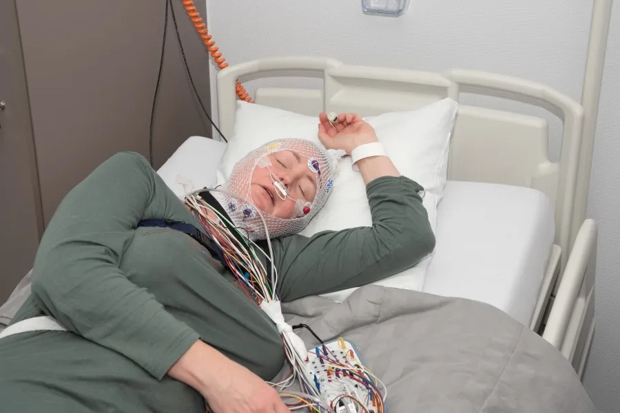 A woman strapped with medical tubes and wires while sleeping in a hospital bed
